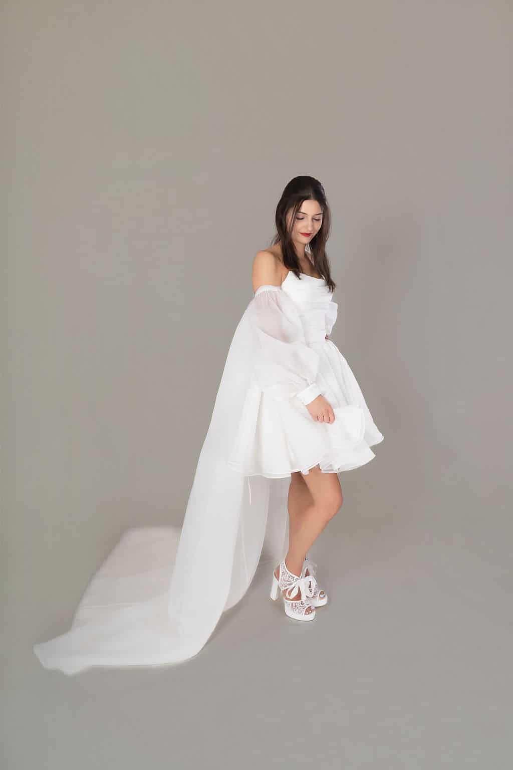 Off-shoulder mini bridal gown with voluminous sleeves and tulle train detail