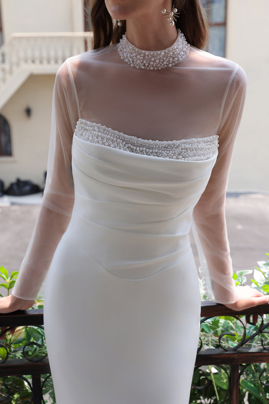 Close-up of beaded neckline, sheer long sleeves and ruched bodice on a mermaid wedding dress