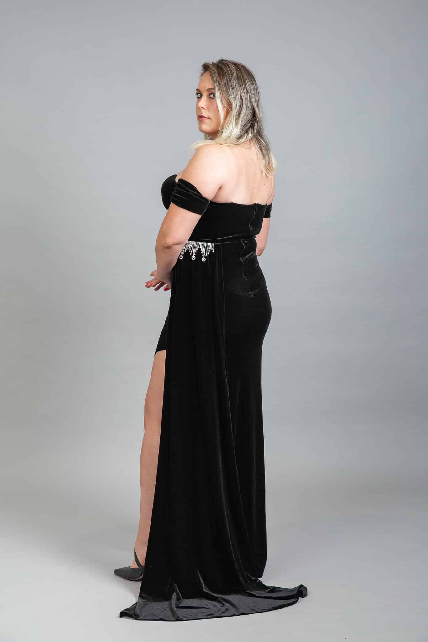 Back view of black velvet gown with off-shoulder design and sweeping train