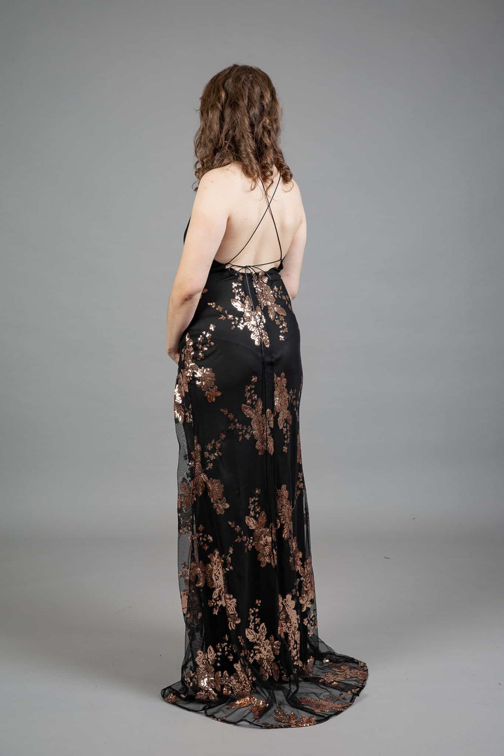 Back view of black halter gown with floral embroidery, criss-cross back straps, and flowing train