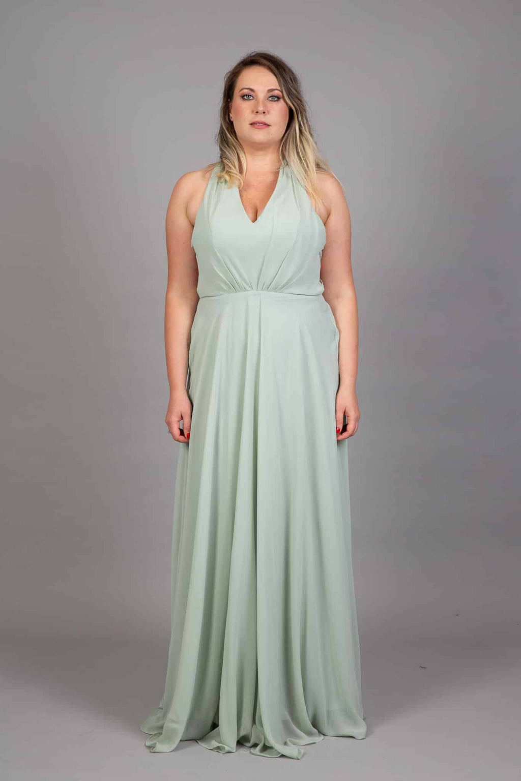 Sage green halter neck chiffon bridesmaids gown with V neckline and floor-length flowing skirt, front view