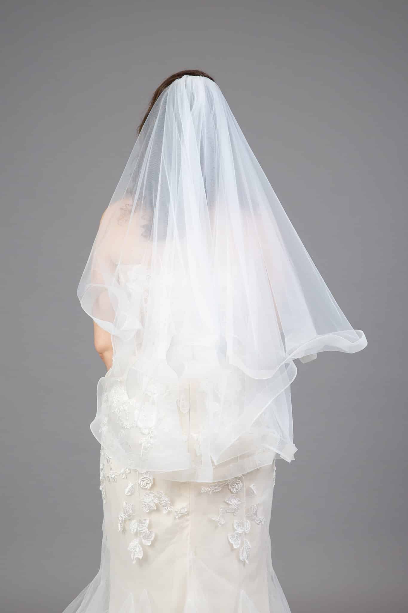 Back view of bride wearing horsehair edge veil with ruffled hem and flowing tulle layers