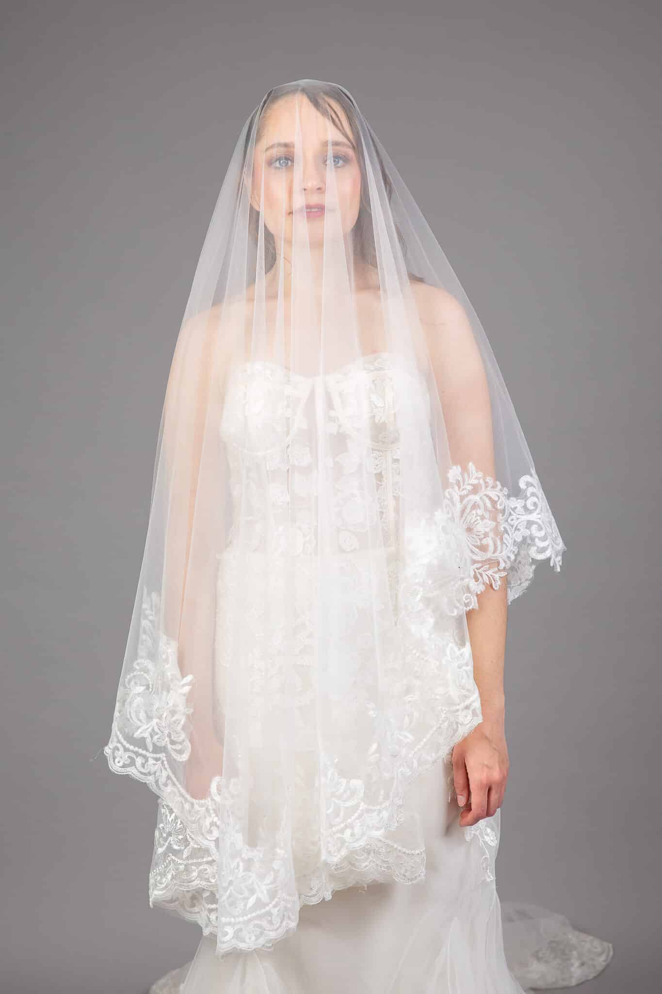 Bride wearing ivory tulle cathedral veil with lace appliqué scalloped edge and blusher, front view – Art Kollocsion Auckland
