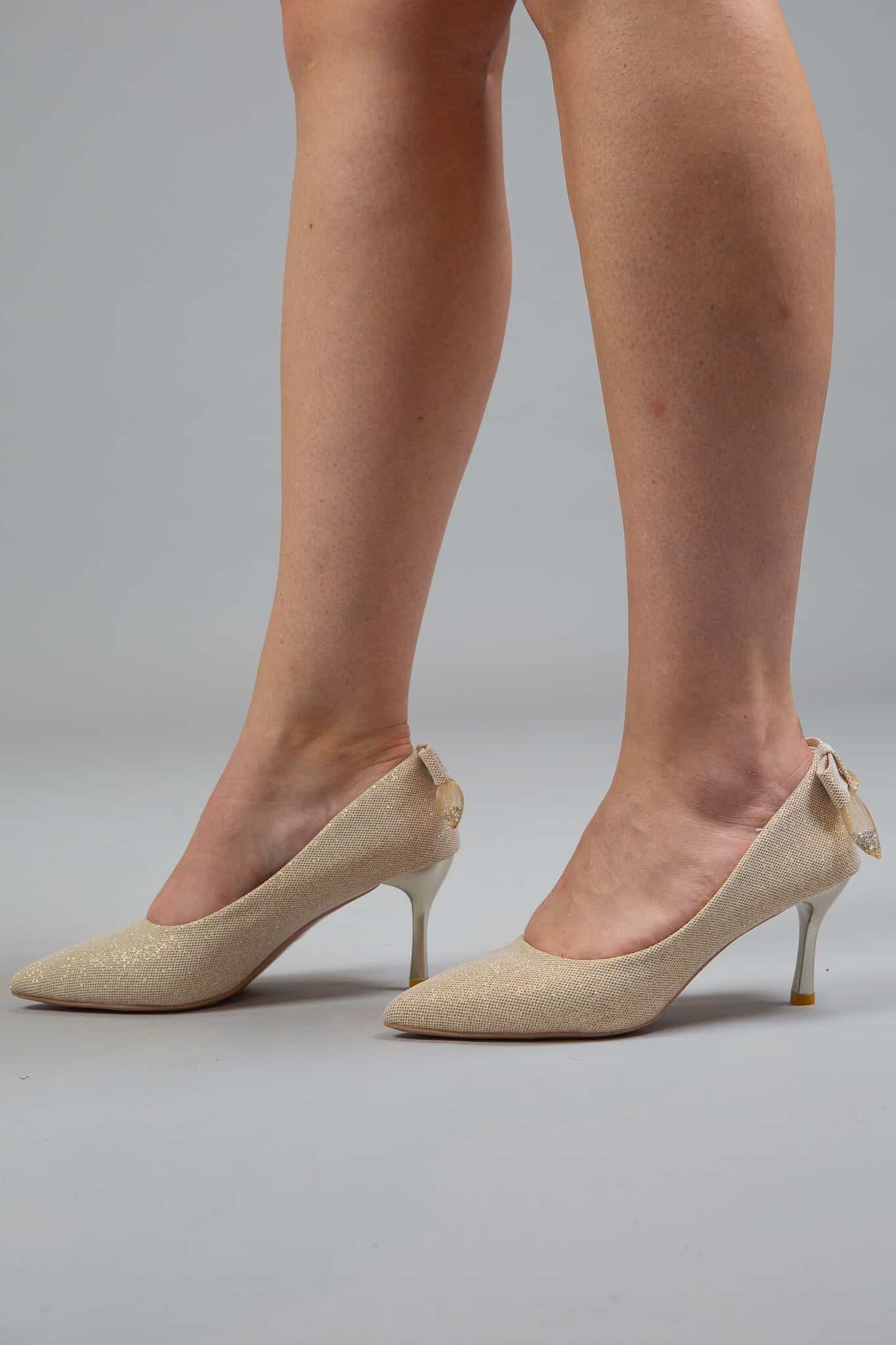 Model wearing matte golden heels with pointed toe, slim heel, and bow detail – Art Kollocsion Auckland
