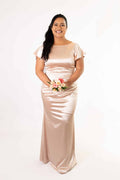 Model in champagne silky satin bridesmaids dress with short flutter sleeves and ruched waist – Art Kollocsion Auckland