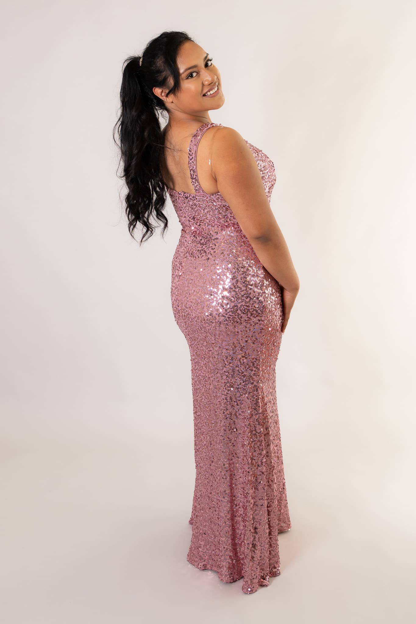 Model wearing dusty pink sequin maxi dress with V-neckline, side profile view - Art Kollocsion