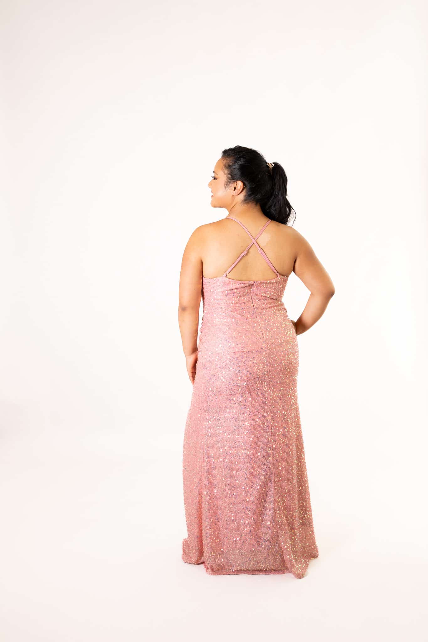 Rear angle of pink sequin formal dress showing crisscross back straps and full maxi length