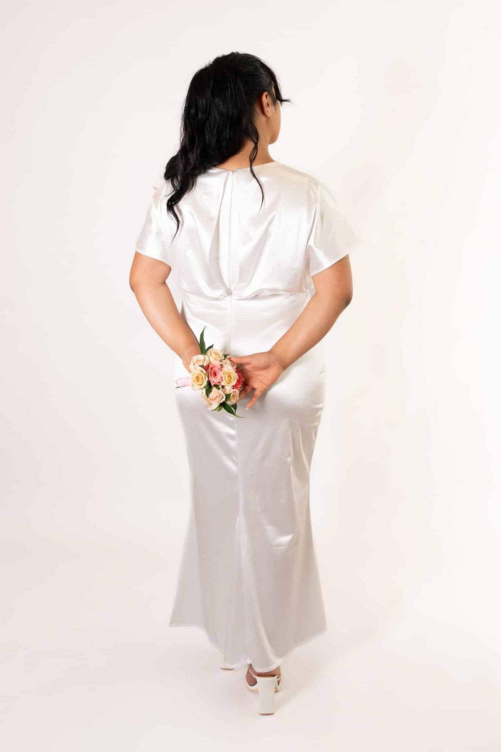 Back view of white short-sleeved bridesmaids dress showing clean back design and flowing satin skirt