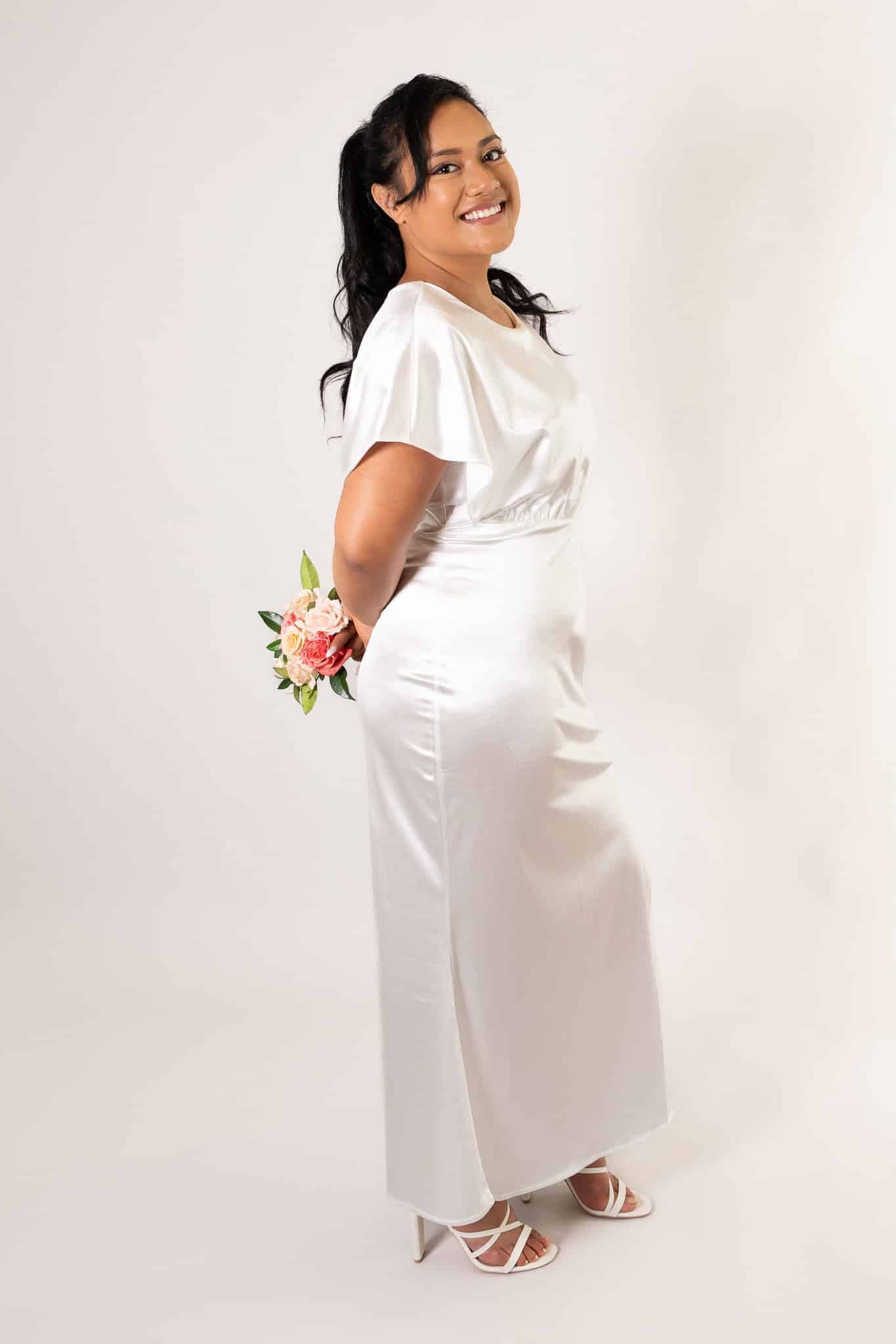 Side profile of white satin bridesmaids dress with short puffed sleeves and elegant drape