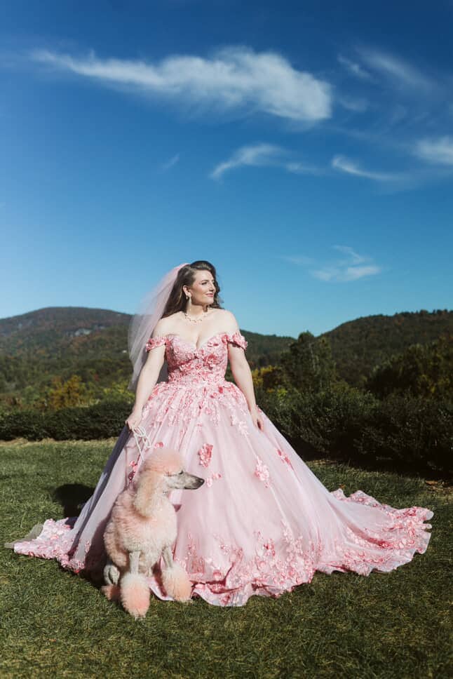 Bride wearing the blush pink fairytale ball gown outdoors with a pink poodle, full skirt spread on grass