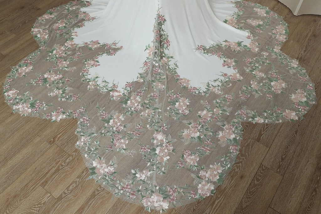 Close-up of frosted floral petal train with pink roses and green foliage detail