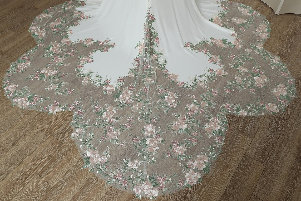 Close-up of frosted floral petal train with pink roses and green foliage detail