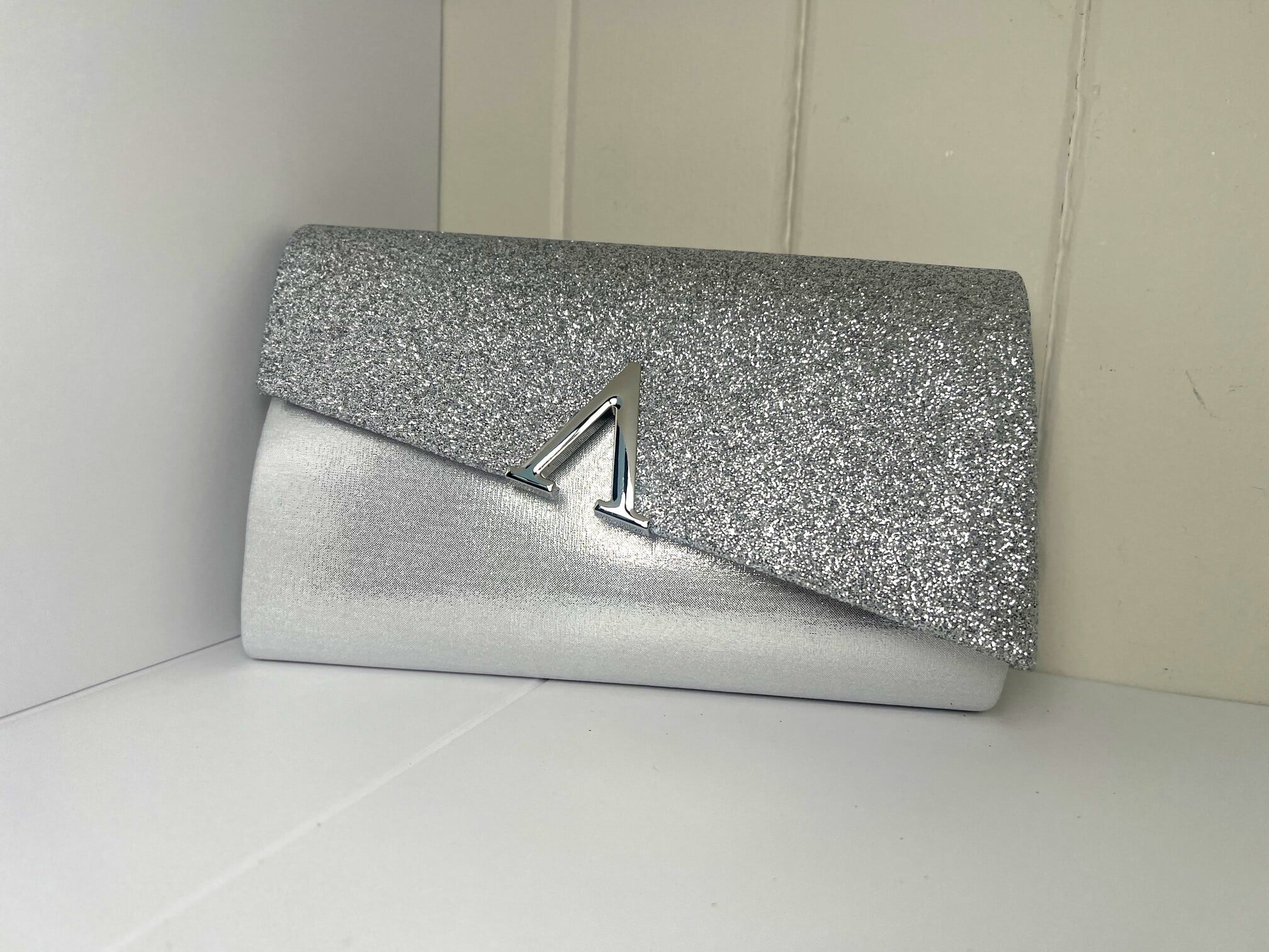 Silver glitter clutch with metallic trim detail and gold chain strap