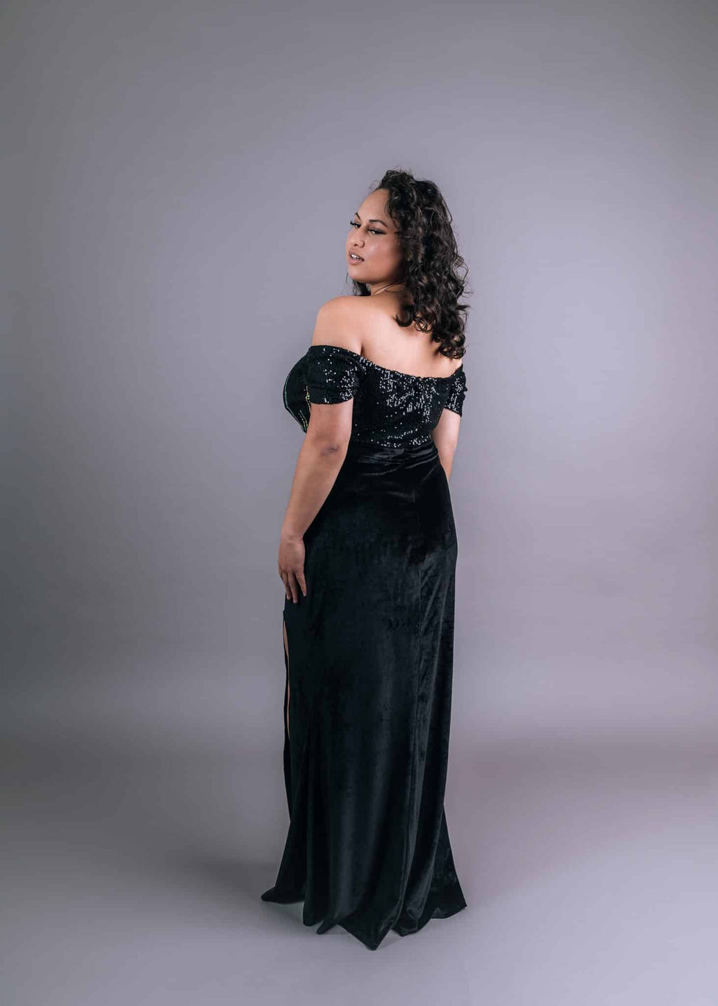 Back view of black velvet dress with sequined off-shoulder bodice and flowing skirt