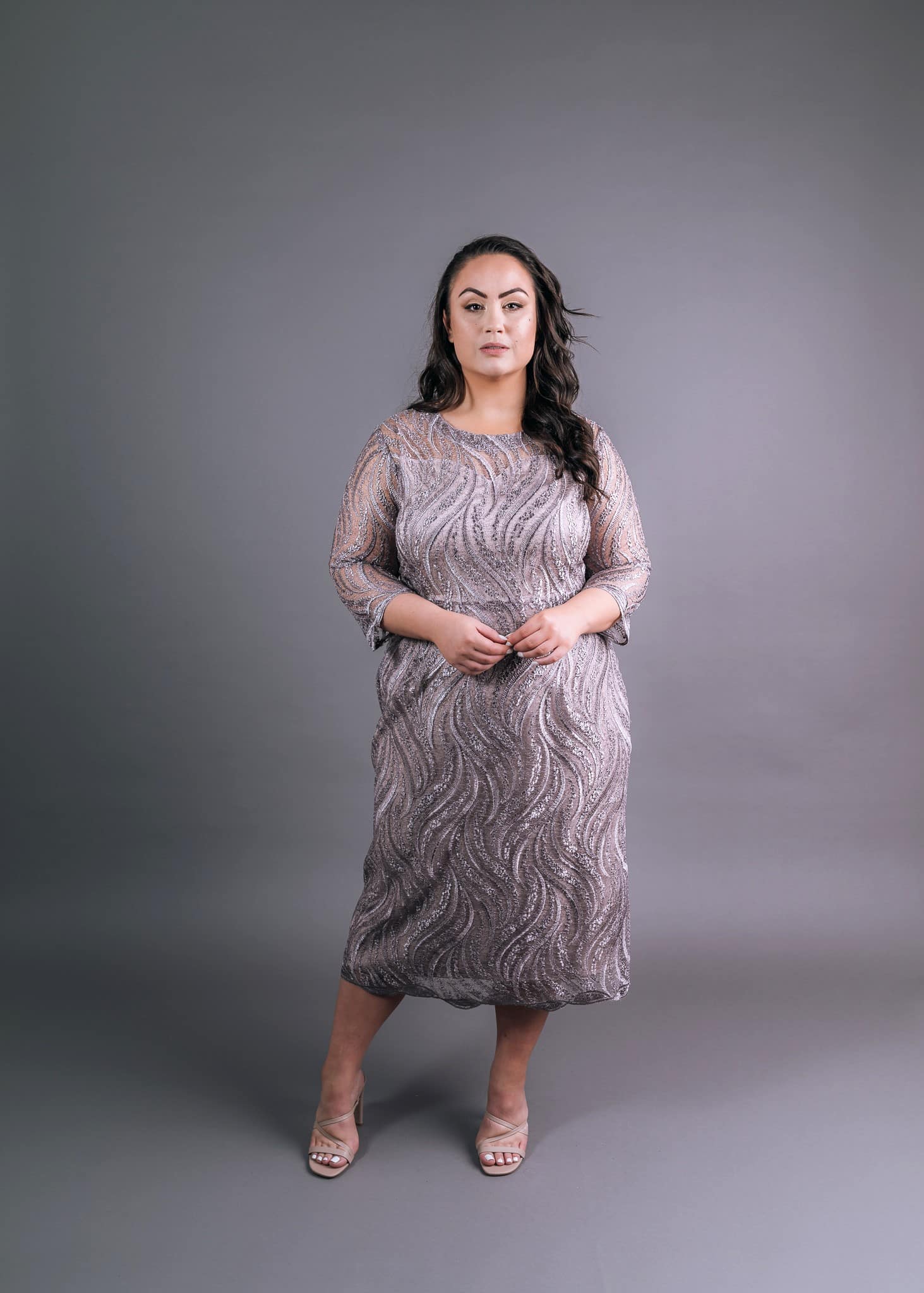 Front view of beige patterned knee-length dress with round neckline and three-quarter sleeves