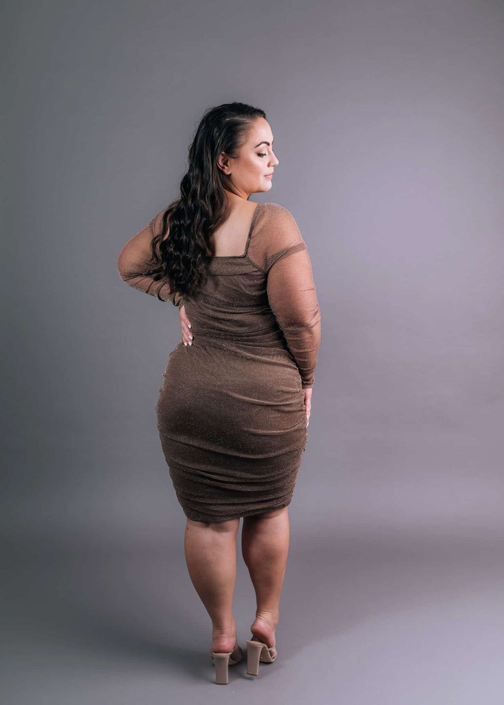 Taupe ruched cocktail dress with sheer mesh sleeves, back and side view showcasing fitted silhouette