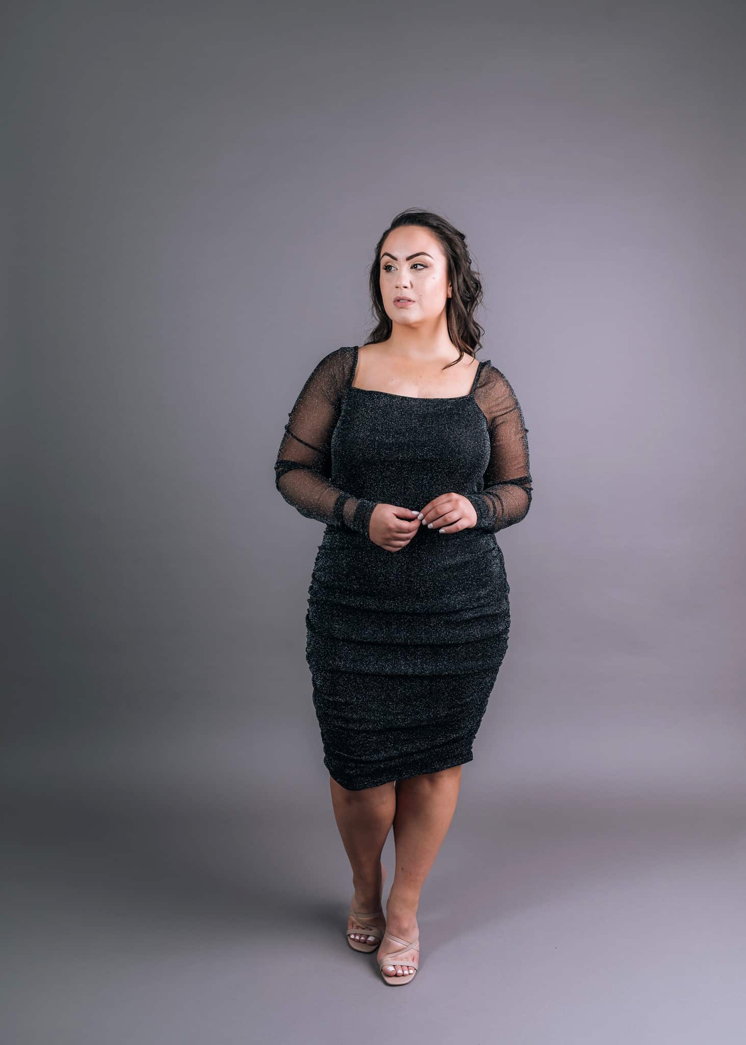 Black shimmery long-sleeved cocktail dress with square neckline and mesh overlay sleeves, front view – Art Kollocsion Auckland
