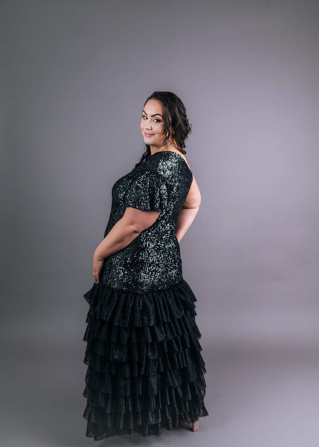 Back view of black glittery show girl dress with short ruffle sleeves and layered tulle hem