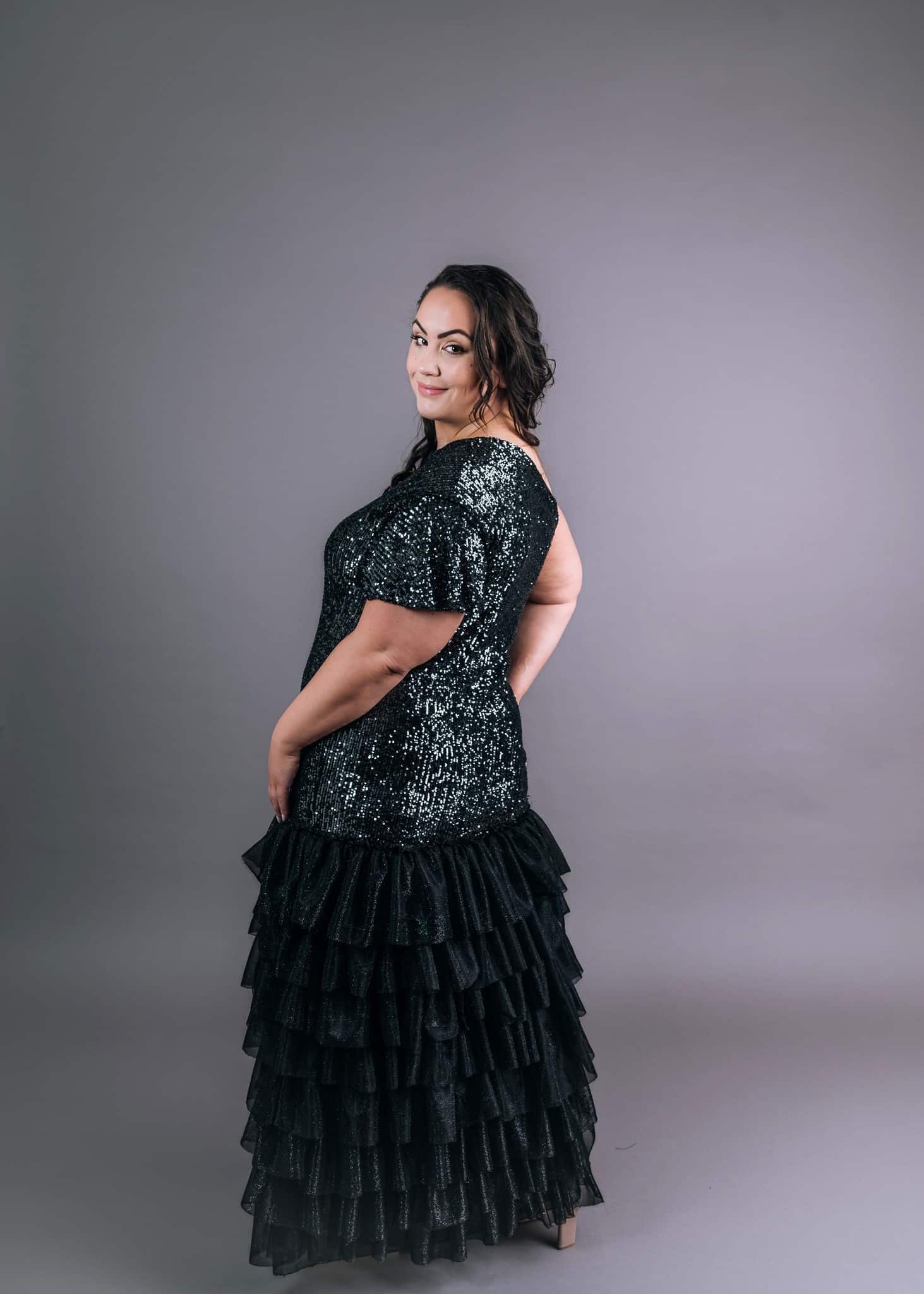 Back view of black glittery show girl dress with short ruffle sleeves and layered tulle hem