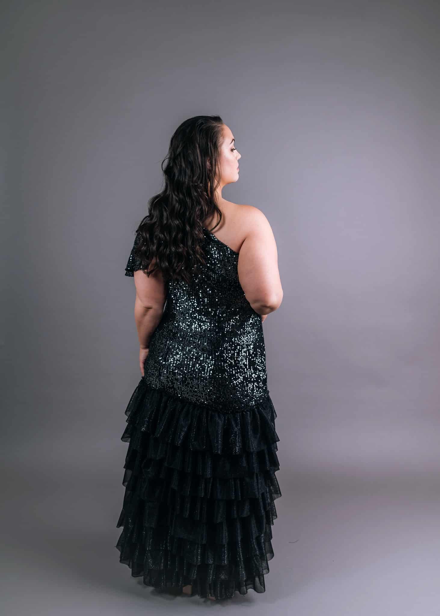 Side profile showing one-shoulder sequin bodice with open back and ruffled tulle layers
