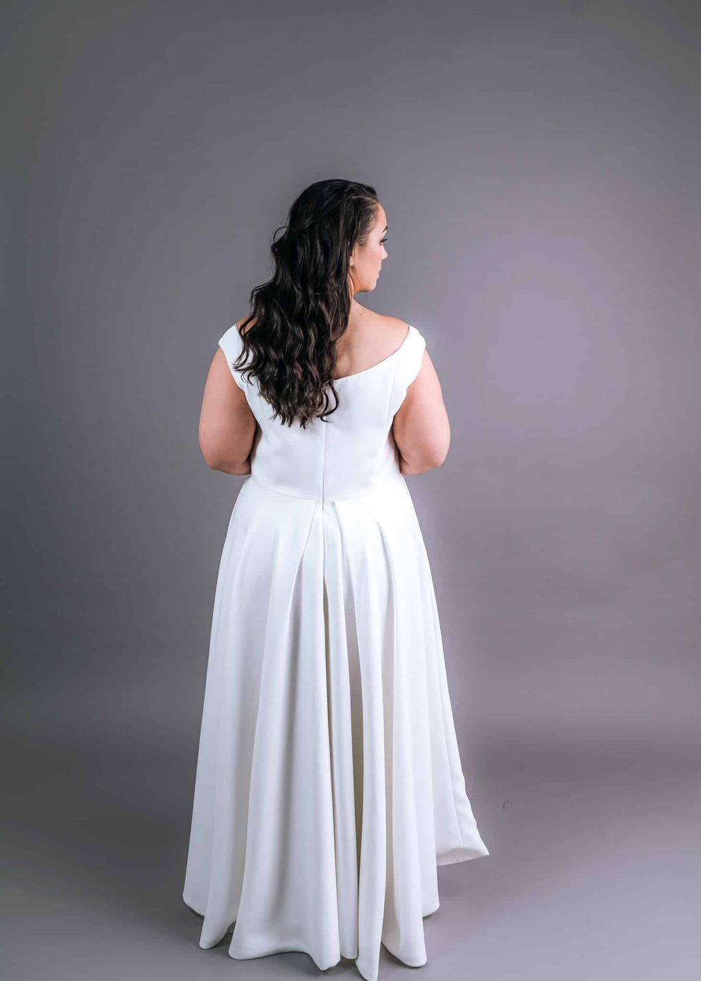 Back view of plus-size wedding gown with scoop neckline and pleated A-line skirt