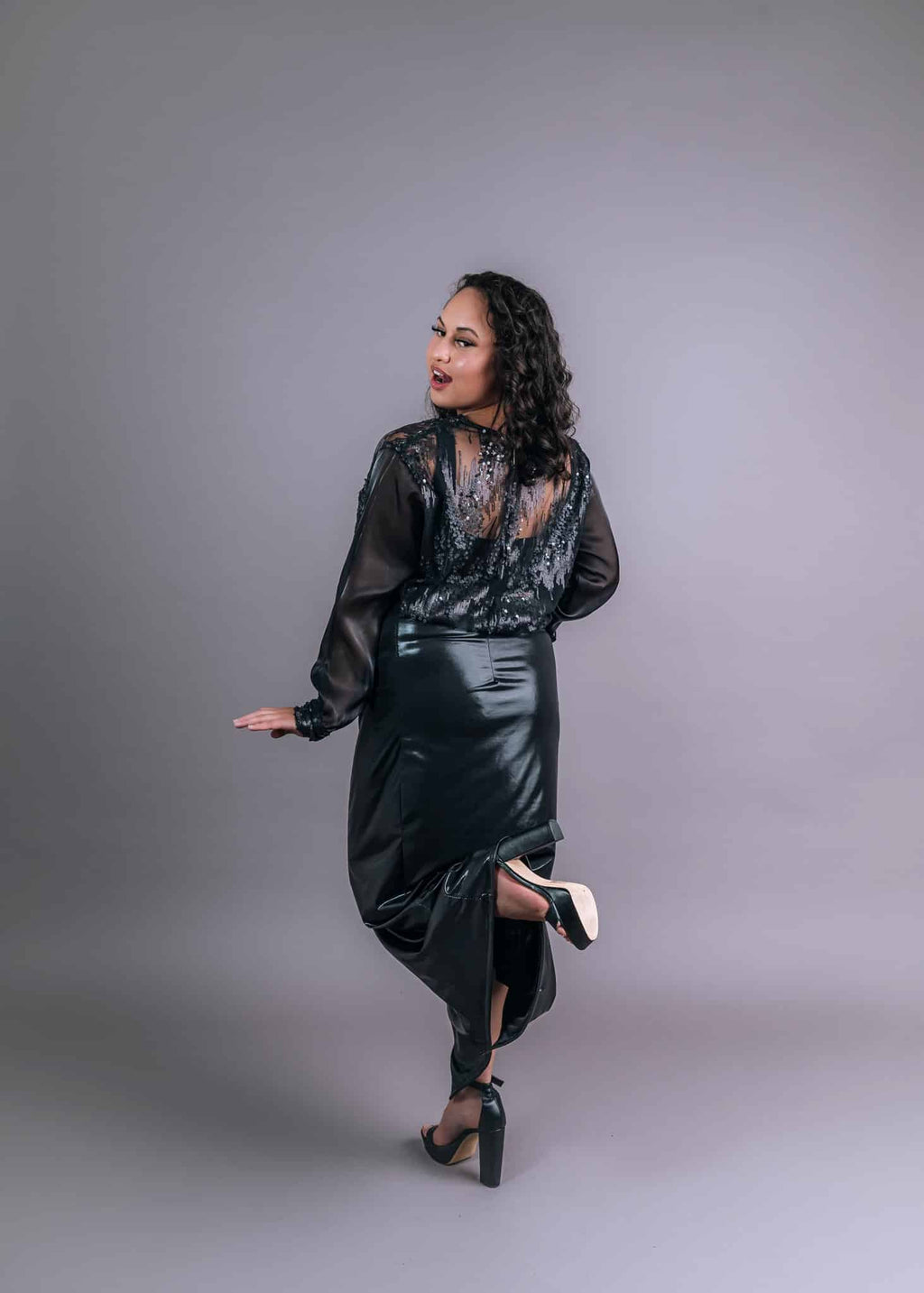 Side profile of black sequin and satin two-piece set with elegant draping, walking pose