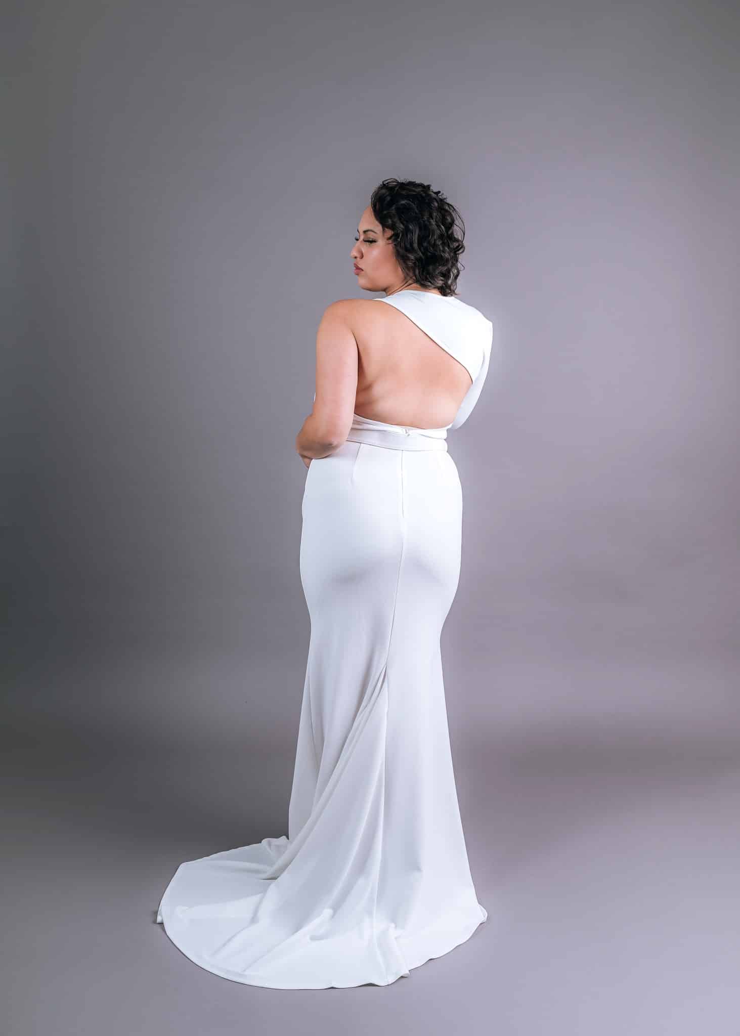 Model in white mermaid silhouette wedding dress showing elegant low-back detail and trailing train
