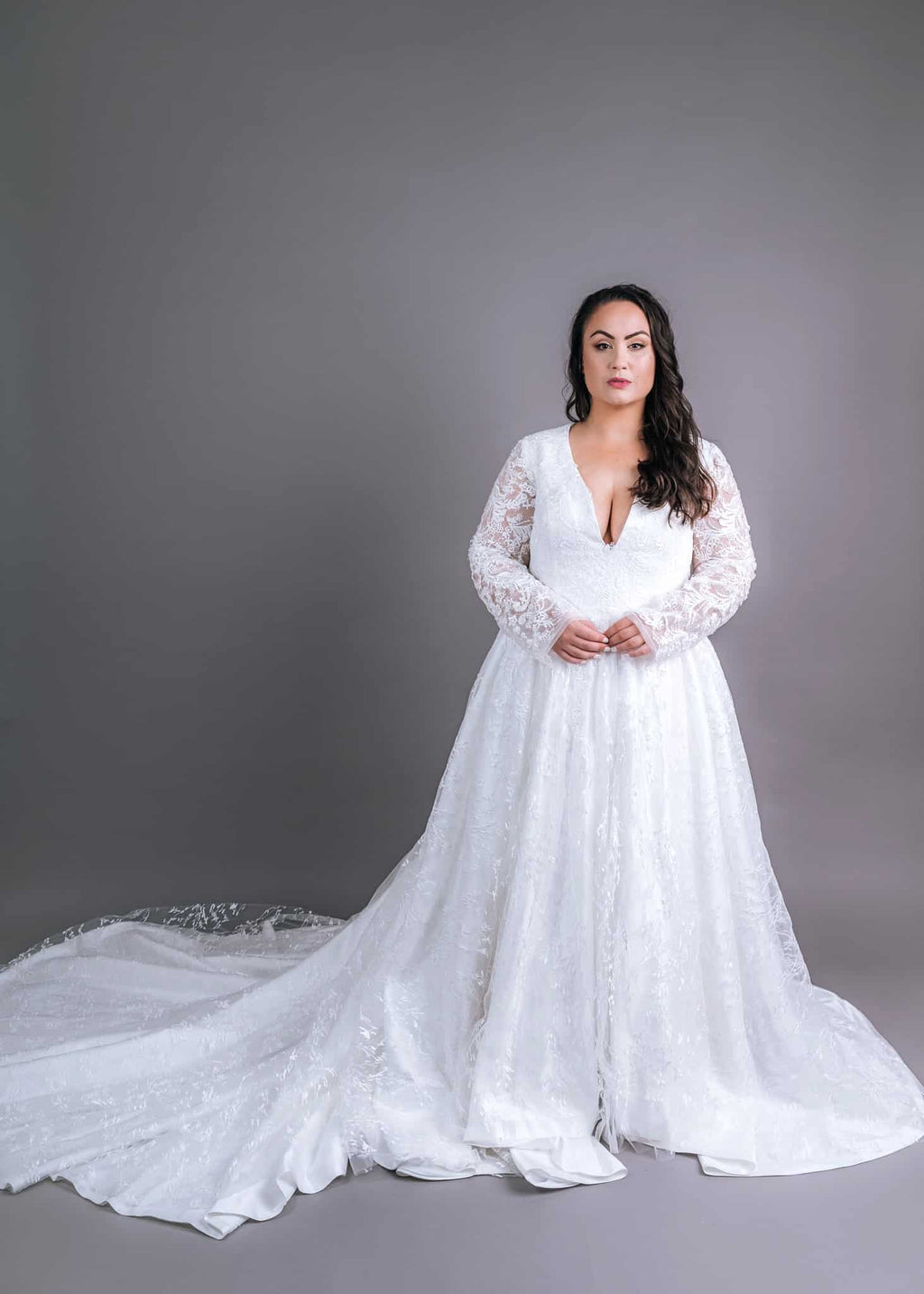 Plunge neckline wedding gown with sheer lace sleeves and full A-line skirt, front view – Art Kollocsion Auckland