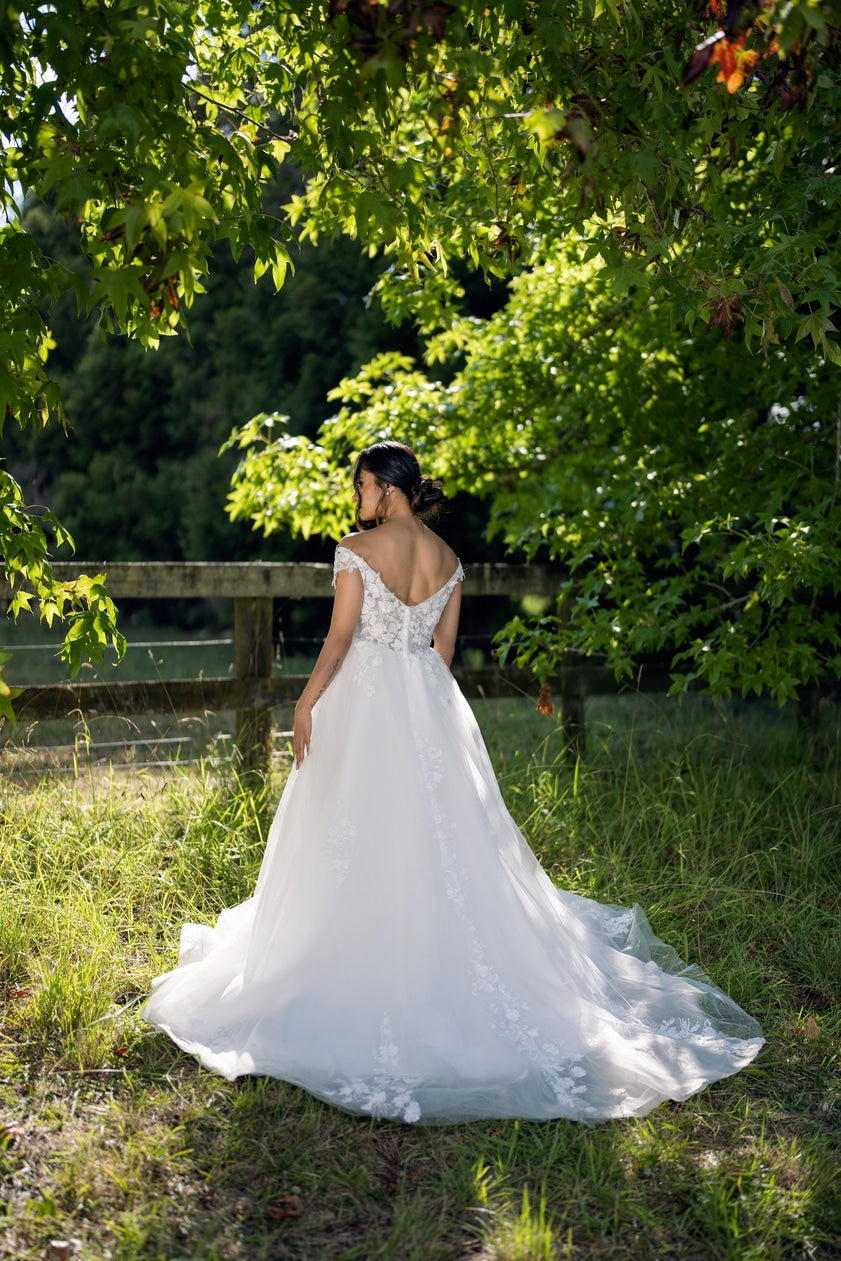 Bride in white off-shoulder wedding gown with flowing train, back view – Art Kollocsion