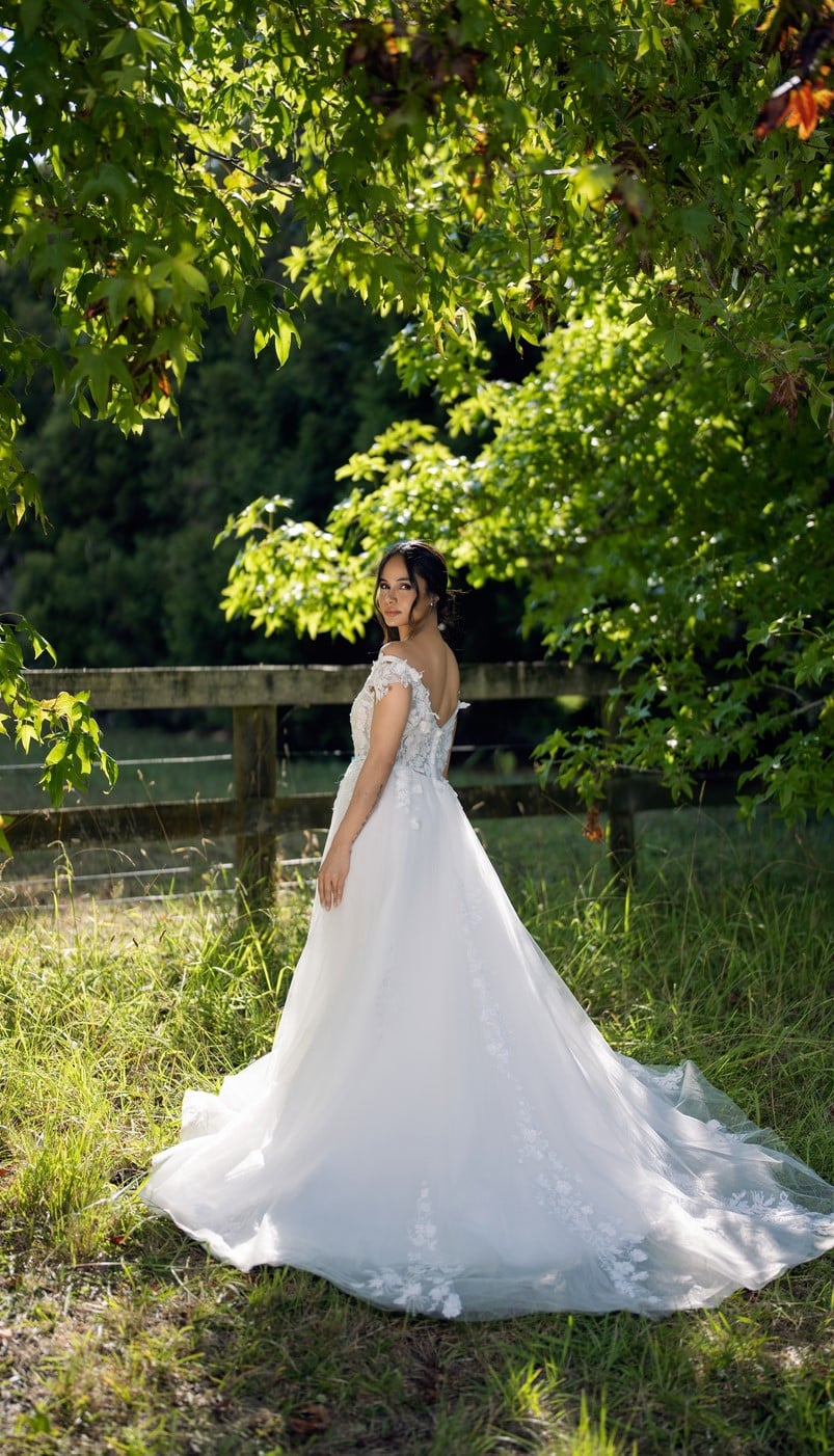 Side profile of off-shoulder wedding gown with elegant silhouette and dramatic train