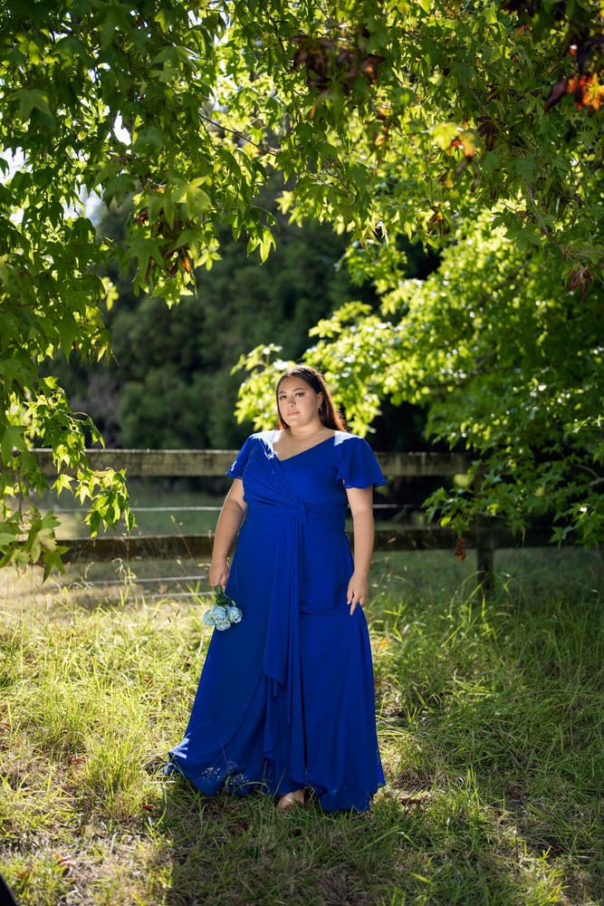 Plus-size bridesmaid dress in cobalt blue with flutter sleeves and cascading draped hem detail