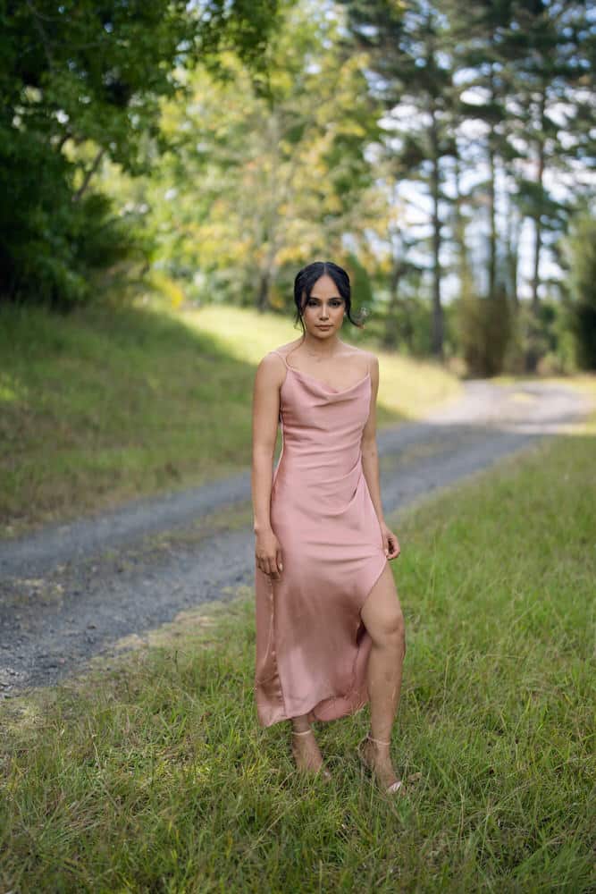 Front view of blush pink satin slip dress with cowl neckline, spaghetti straps and side split, midi length