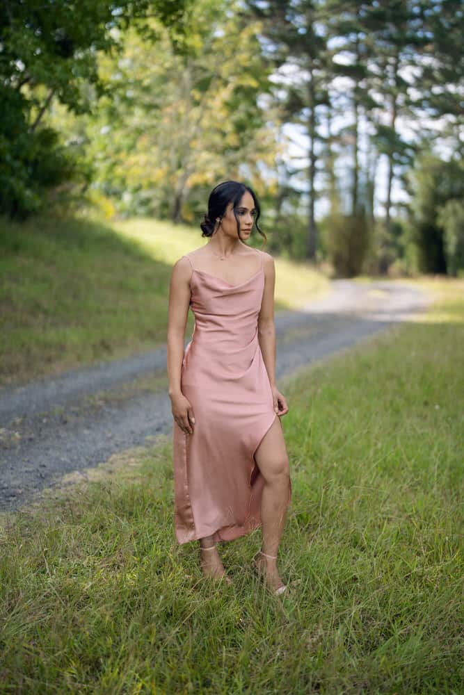 Dusty pink satin Cowl Neck Bridesmaids Dress with leg split, model walking outdoors – Art Kollocsion Auckland