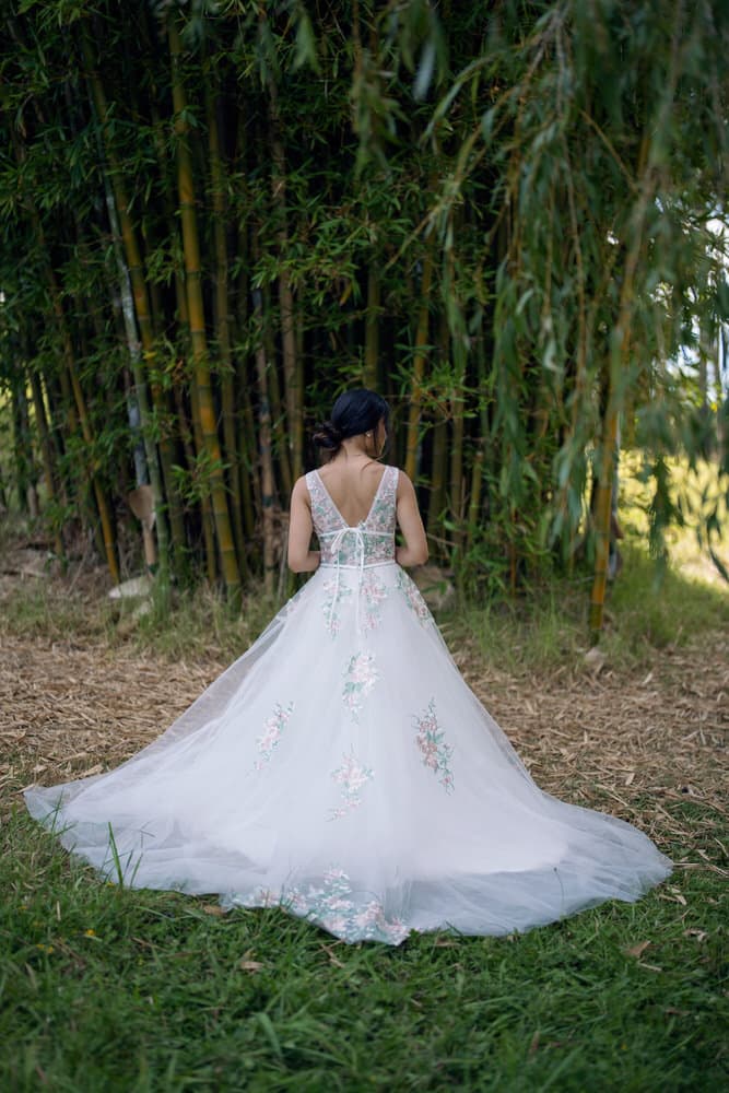 Back view revealing low V-back and flowing train with scattered floral appliques