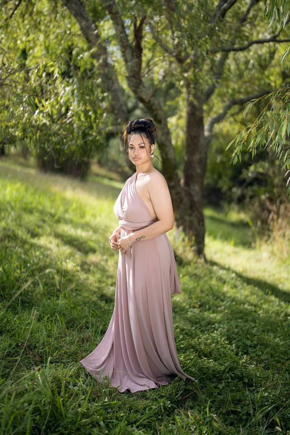 Model in dusty pink Classic Multiway Infinity Dress with halter wrap bodice, side view outdoors – Art Kollocsion Auckland
