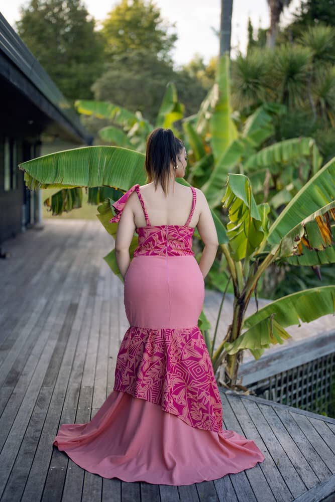 Back view of pink mermaid gown with geometric print, low back strap detail, and flowing train