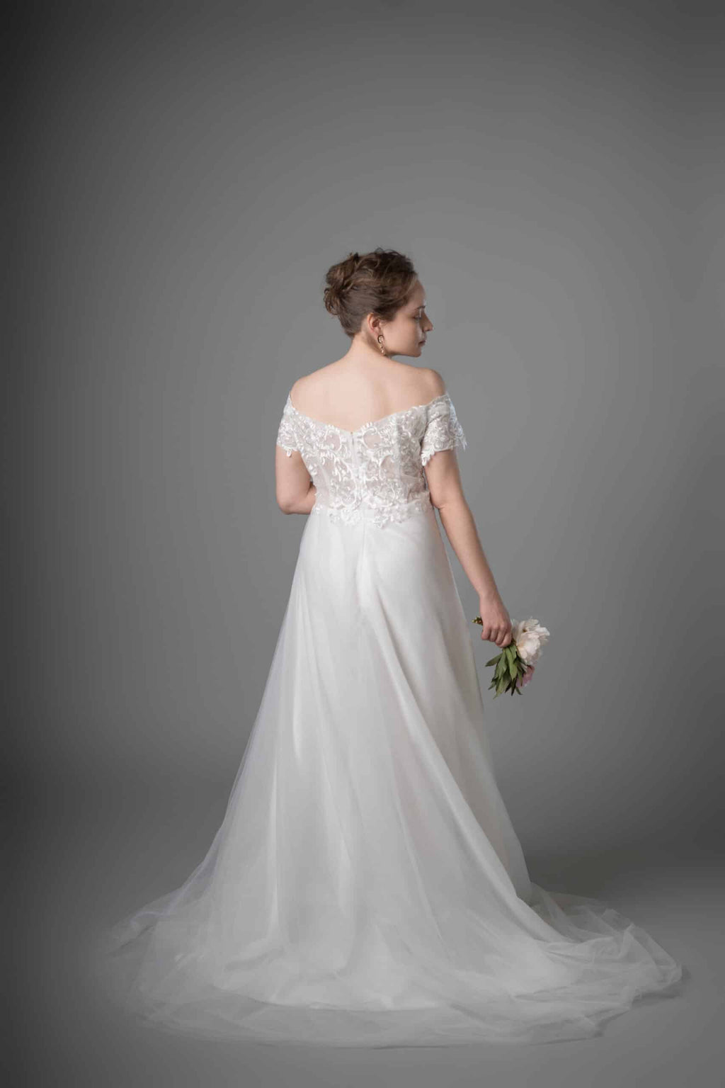 Back view of off-shoulder wedding dress showcasing delicate lace bodice and flowing tulle train