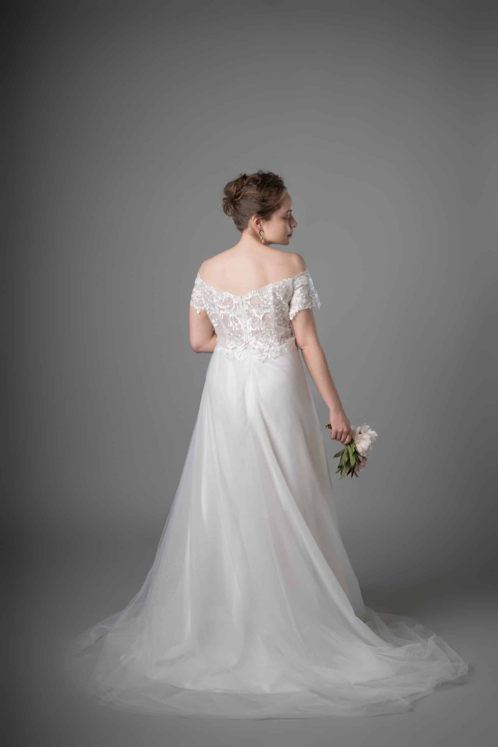 Back view of off-shoulder wedding dress showcasing delicate lace bodice and flowing tulle train