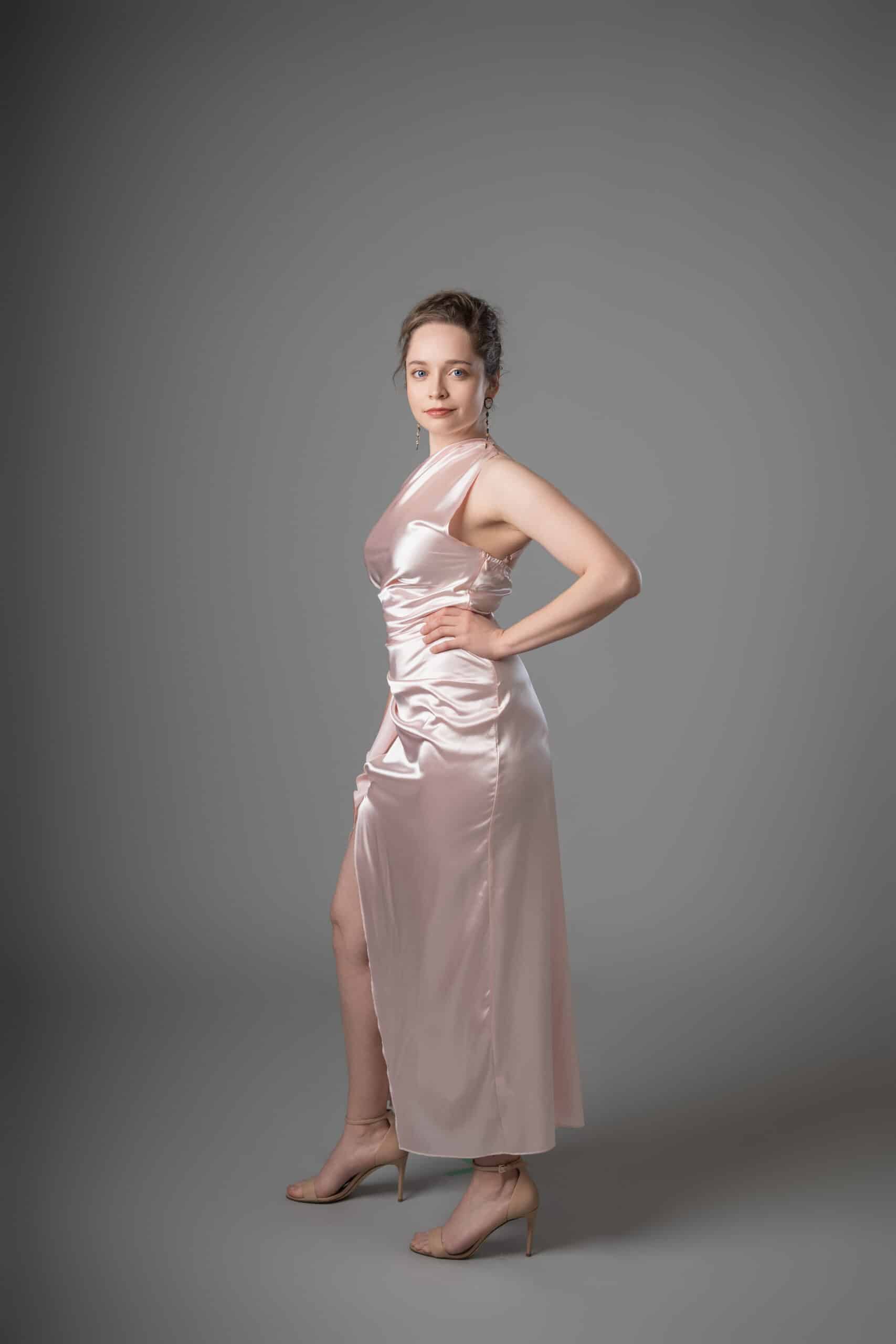 Side view of blush satin gown with one-shoulder neckline and draped ruching detail