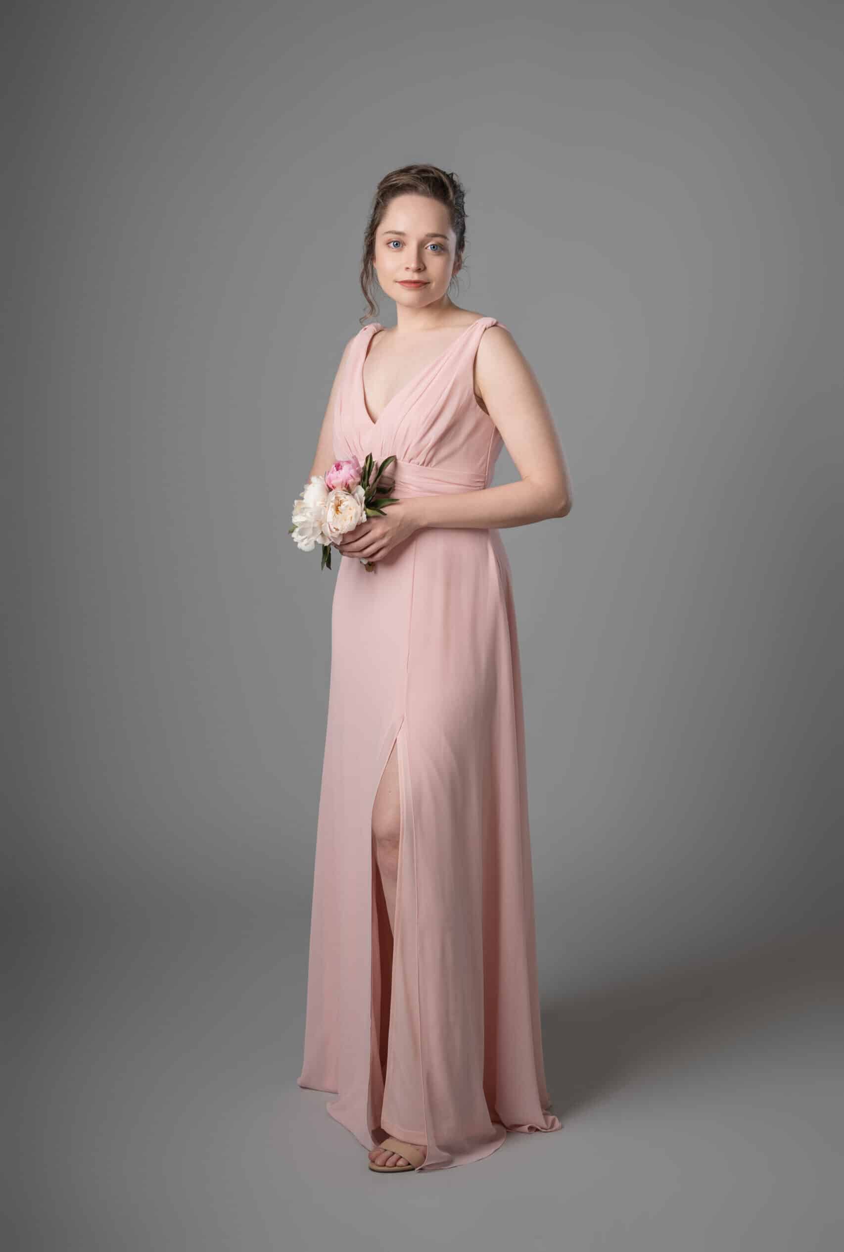 Model wearing sleeveless pink chiffon bridesmaids dress with V neckline and flowing skirt – Art Kollocsion Auckland