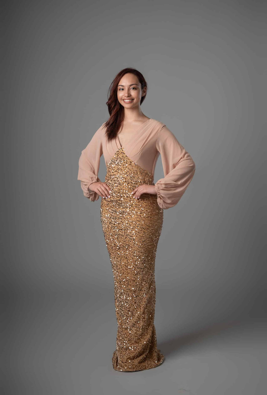Front view of long sleeve maxi dress featuring blush sleeves and shimmering gold sequin bodice