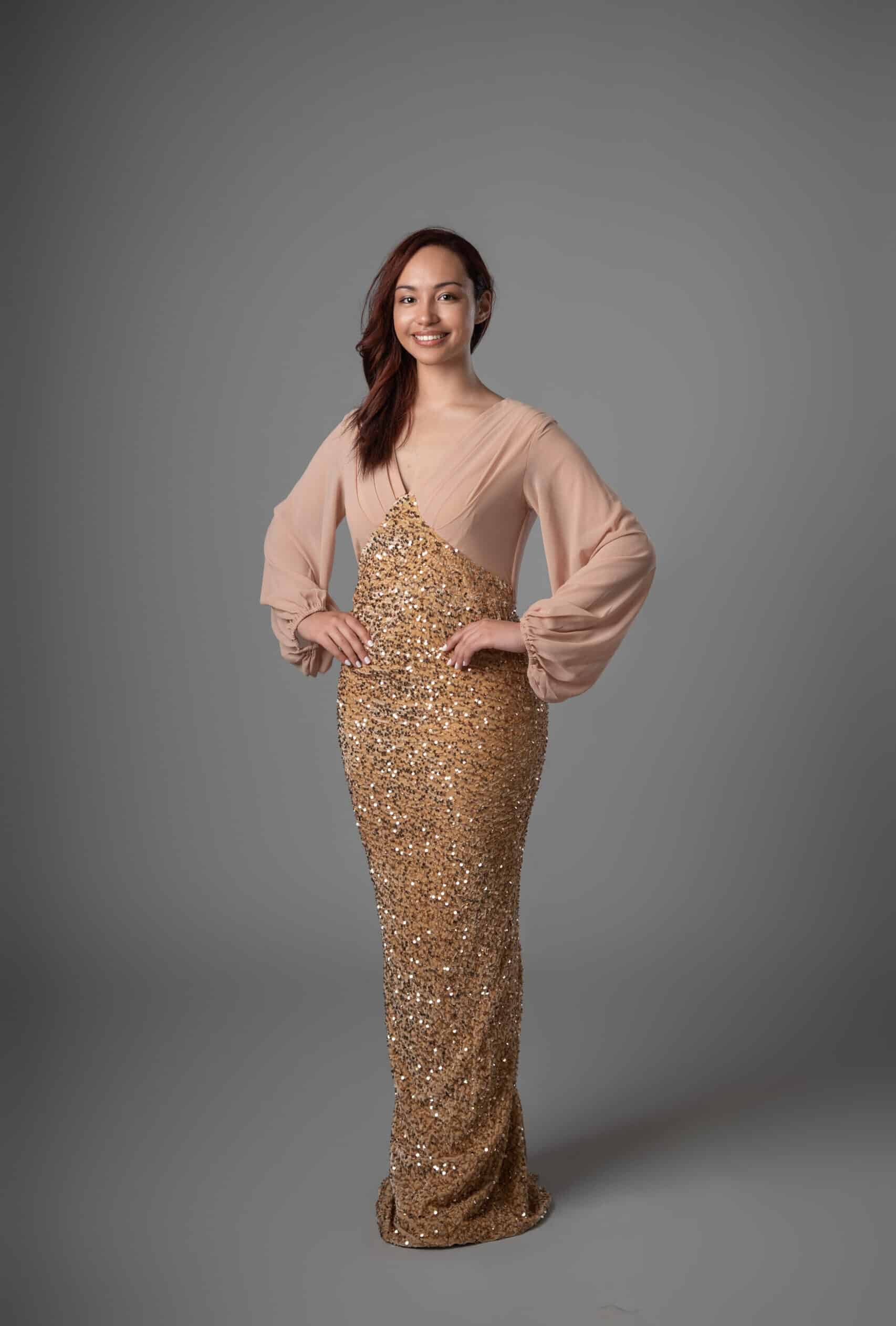Front view of long sleeve maxi dress featuring blush sleeves and shimmering gold sequin bodice