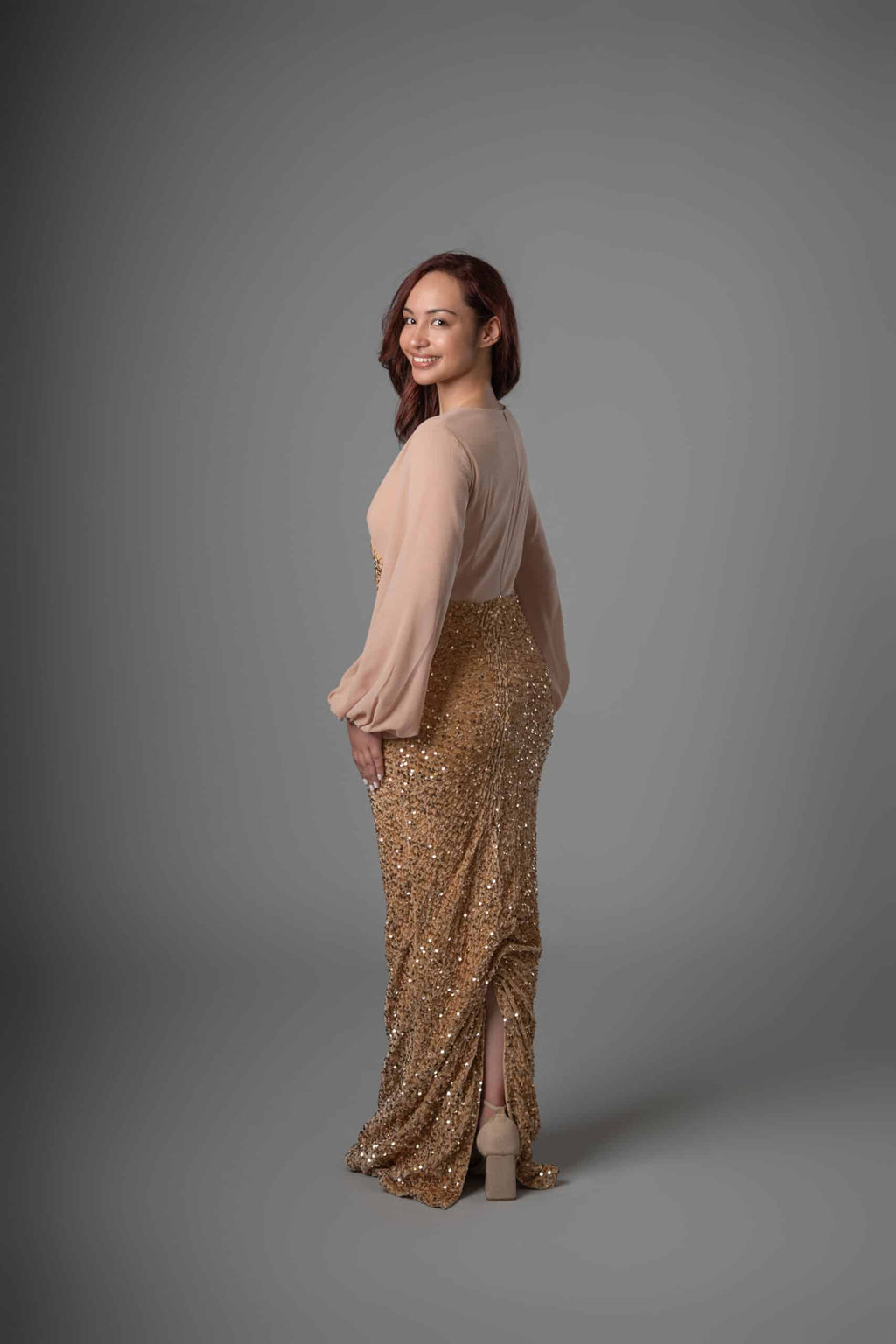 Side view of champagne and gold sequined maxi dress with elegant draped skirt