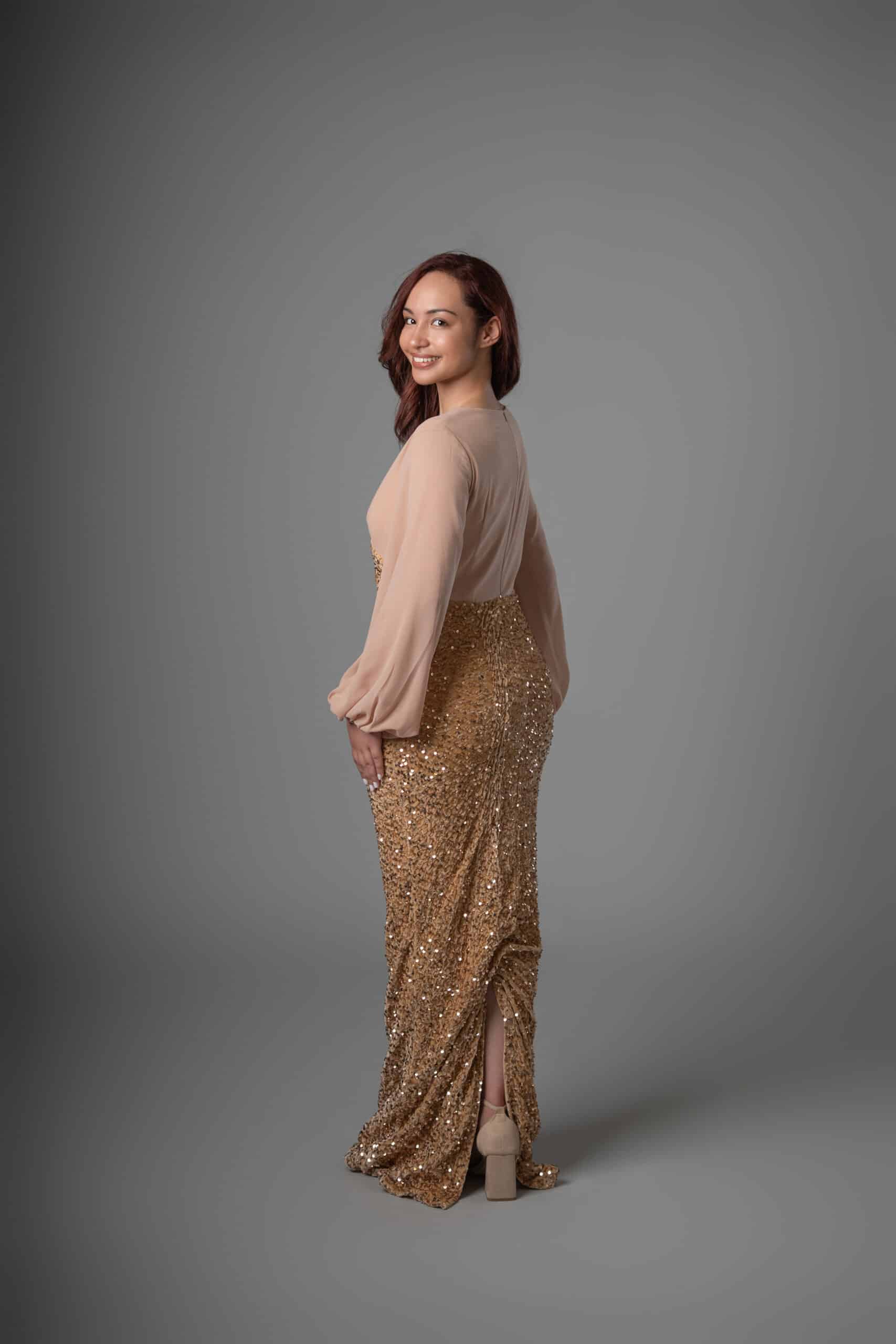 Side view of champagne and gold sequined maxi dress with elegant draped skirt