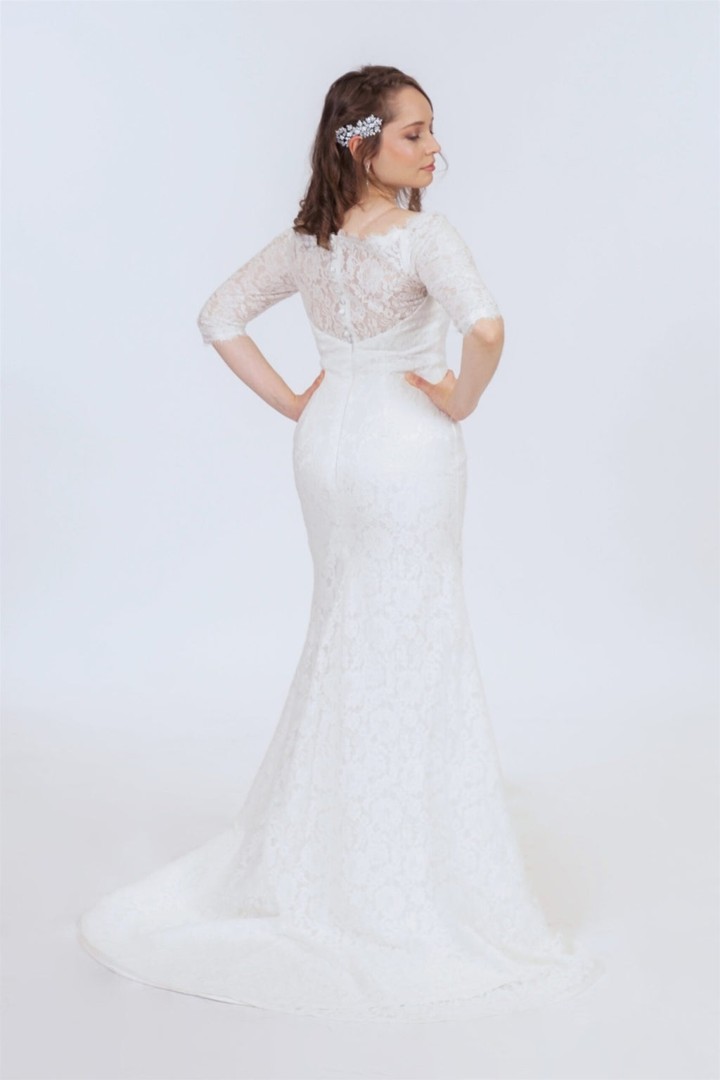 Bride wearing guipure lace wedding dress with three-quarter sleeves and fitted silhouette, side profile view