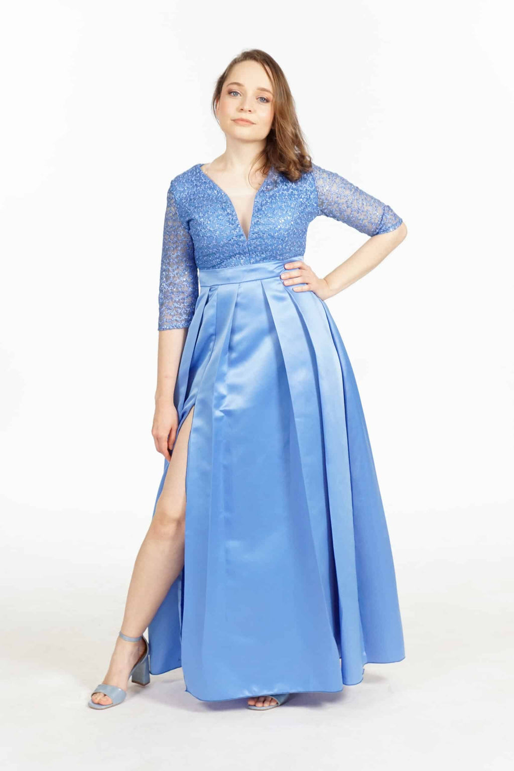 Model in blue sequined bridesmaids dress with V-neckline, three-quarter sleeves, and pleated satin skirt with side slit