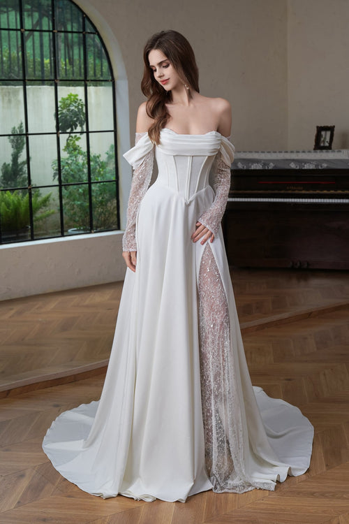 Model in ivory satin A-line off shoulder wedding dress with sheer beaded sleeves and lace-lined split skirt