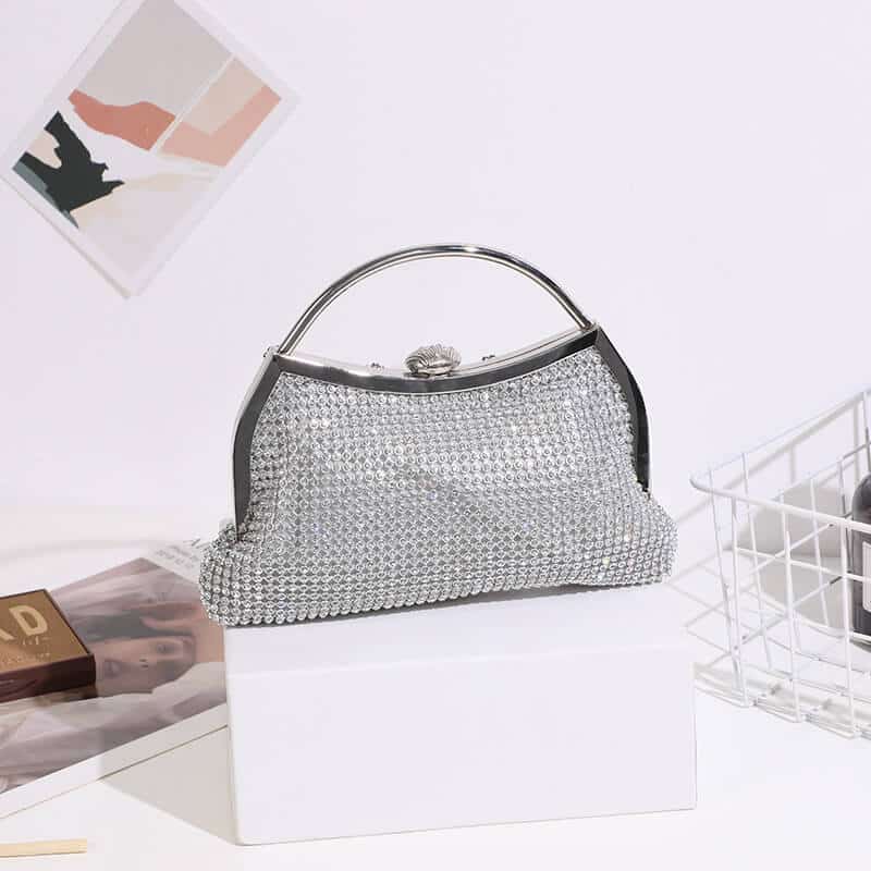 Silver rhinestone clutch bag with metal top handle and shell clasp, styled front view