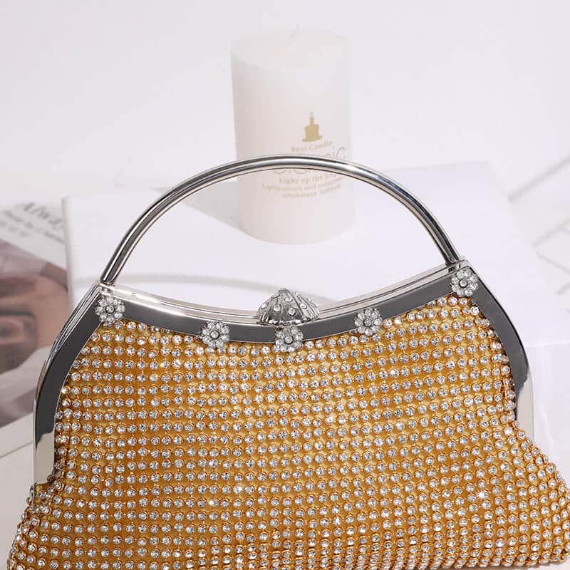 Close-up of gold clutch bag with rhinestone clasp and crystal flower accents along the silver frame