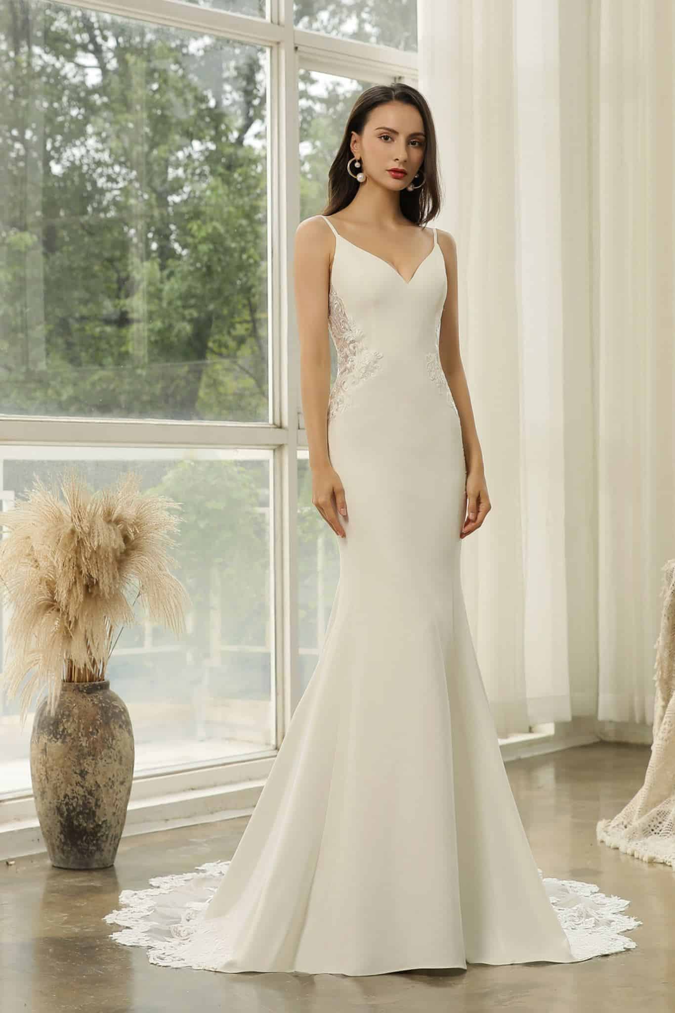 Sleeveless ivory mermaid wedding dress with side lace panel detail and flowing train